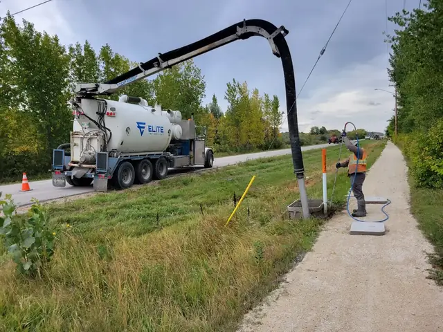 Elite Vac Services hydrovac truck exposing a utility beside a paved pathway